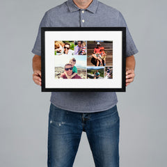 A man holds a black-framed custom photo collage print with a white mat against a solid gray background. The image is 30x20cm and the frame is 44x34cm. 